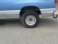 A blue 2010 Ford Econoline with a flat rear tire featuring a white rim and worn tread