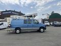 A blue 2010 Ford Econoline van with a raised platform and equipment on top parked on a lot