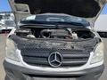A 2010 Mercedes-Benz Sprinter van with the hood raised revealing the engine compartment and visible components like the air intake and coolant reservoir