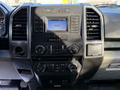 The dashboard of a 2018 Ford F-150 featuring a radio display and climate control knobs in a black interior setup