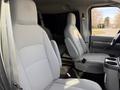 Two gray cloth seats of a 2011 Ford Econoline van are visible in the foreground with a center console in between them