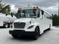 A white 2015 Spartan School Bus with orange roof lights and prominent front grille parked in a lot