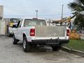A white 2011 Ford Ranger truck with a silver metal flatbed and black bumpers parked at a location with industrial elements in the background