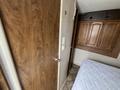 A 2013 Outdoor Wind River trailer interior featuring wooden cabinetry and a partially made bed with a mattress on top