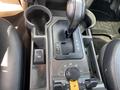 The center console of a 2006 Land Rover LR3 featuring gear shift levers cup holders and various control buttons