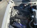 A 2012 GMC Savana vehicle with visible components under the hood including a battery and various engine parts
