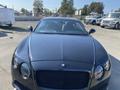 A 2015 Bentley Continental GT with a sleek black exterior and luxurious interior features positioned prominently in the foreground