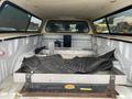 A 2018 Ford F-150 truck bed with a storage box and rubber floor mats inside