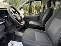 Interior view of a 2023 Ford Transit showing the driver's seat steering wheel and dashboard with a divider behind the front seats