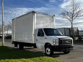 A 2019 Ford Econoline box truck with a white exterior and no visible markings parked on a grassy area