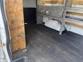 Interior of a 2016 GMC Savana cargo van showing a wooden panel and a black rubber floor with metal shelving on the sides