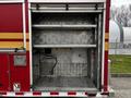 The rear compartment of a 2009 Spartan Gladiator fire truck with metal shelves and a circular white panel inside