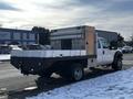 A 2011 Ford F-450 SD with a flatbed design featuring a metal toolbox and additional storage compartments on the side
