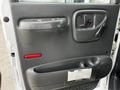 The interior door panel of a 2006 GMC C5000 featuring a black armrest handle and a storage compartment below with a label