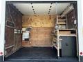 A 2013 Ford Econoline van with an open cargo area featuring wooden paneling and metal shelving units inside