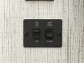 A black control panel featuring two switches labeled for fan and vent operation with positions for on off and open close