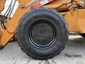 A close-up view of a black tire from a 2005 Case 570 construction vehicle showcasing its tread pattern and wheel rim