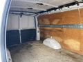 Interior view of a 2023 GMC Savana cargo van featuring a spacious empty cargo area with wooden paneling and a flat floor