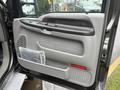 Interior door panel of a 2006 Ford F-450 SD with a handle speaker grille and storage compartment visible