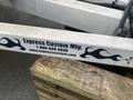 A close-up of a metal trailer frame with flames graphic and branding that reads Express Custom Mfg and contact details for the company