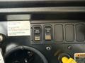 A close-up of a control panel featuring buttons labeled DISAB TRAC ENAB PARKD REGEN with a yellow handle and a sticker for emergency contact information