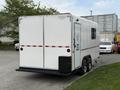 A white 2025 Shuttle Office trailer with double doors and a small black storage compartment on the side mounted on a dual axle chassis