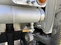 Close-up of a silver metal valve attached to a pipe on a 2009 International 7500 truck's engine system with a circular gauge beneath it