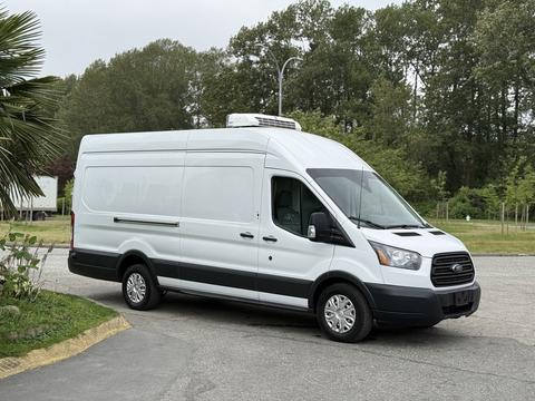 A 2017 Ford Transit van with a white exterior and a black stripe along the bottom parked at an angle