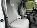 Interior of a 2013 Ford Econoline featuring two gray cloth seats with seat belts and a center console between them