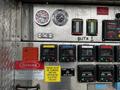 Control panel of a 2009 Spartan Gladiator featuring gauges switches and warning labels related to pump operation and safety