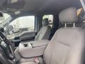 The interior of a 2017 Ford F-550 featuring two gray fabric front seats and a center console with storage space