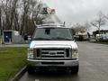 A 2009 Ford Econoline van with a white body and a raised bucket on top for aerial work, featuring a blue stripe on the front and a large grille with headlights