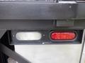 Close-up of two lights on a vehicle with one clear light on the left and one red light on the right mounted on a black surface