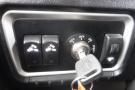 A close-up view of the ignition panel in a 2015 Kenworth T660 featuring two toggle switches and a key ignition with a key inserted