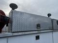 A silver diamond plate tool box mounted on the top of a truck with two mounted floodlights attached on either side