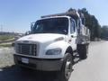 2005 Freightliner M2 106 Medium Duty truck with a white cab and silver cargo bed parked on the side of the road