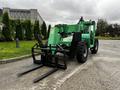 A green 2014 JLG 10054 telehandler with a front-mounted fork attachment and large wheels positioned on a paved surface