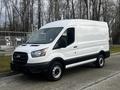 A 2020 Ford Transit van in white with a black stripe along the bottom facing slightly left with its side doors closed and wheels visible