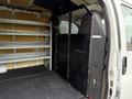 A 2014 GMC Savana interior showing a partition wall, metal mesh grille, and organized shelving units for cargo storage