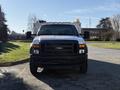 A white 2009 Ford F-550 truck with a black grille and multiple amber lights on the roof facing forward