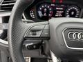 Close-up of the steering wheel of a 2024 Audi Q3 showing control buttons and the Audi logo