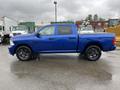 A blue 2019 RAM 1500 Classic pickup truck with a double cab and black wheels parked on a wet surface