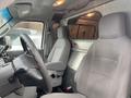 Interior view of a 2011 Ford Econoline showing two gray front seats with seatbelts and a metal partition behind them