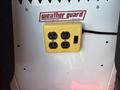 A yellow power outlet with four receptacles and a switch mounted on a white panel in a vehicle