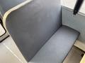 A grey vinyl bench seat designed for a bus or large vehicle with a smooth surface and a curved backrest