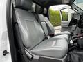 Two grey vinyl seats in the cab of a 2011 Ford F-550 with seatbelt and armrest visible
