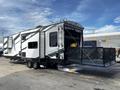 A 2022 Heartland Torque travel trailer with a sleek design featuring black and white exterior colors and a drop-down patio deck at the rear