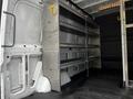 A 2020 Mercedes-Benz Sprinter interior featuring metal shelving units along the sides and a spacious cargo area with a rubber mat flooring