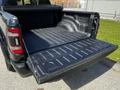 A 2019 RAM 1500 pickup truck with its tailgate down revealing a black lined truck bed
