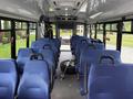 Interior of a 2020 Chevrolet Express with multiple blue seats arranged in rows and a spare tire on the floor in the center aisle